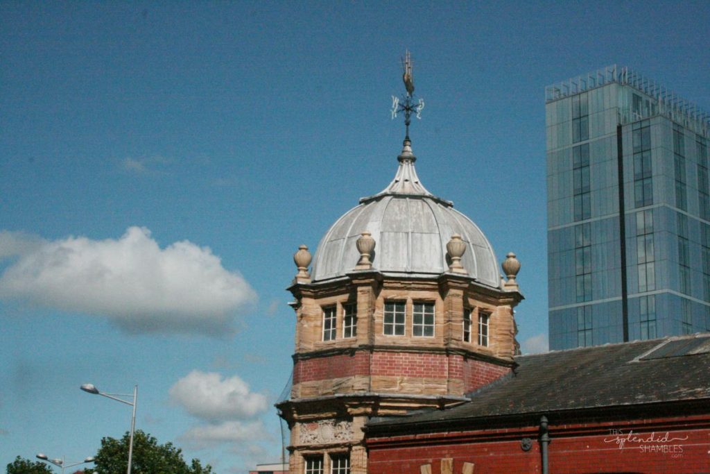 Old building's dome roof surrounded by modern buildings, rising into the blue sky. How to spend a day in Bristol, England. This Splendid Shambles.