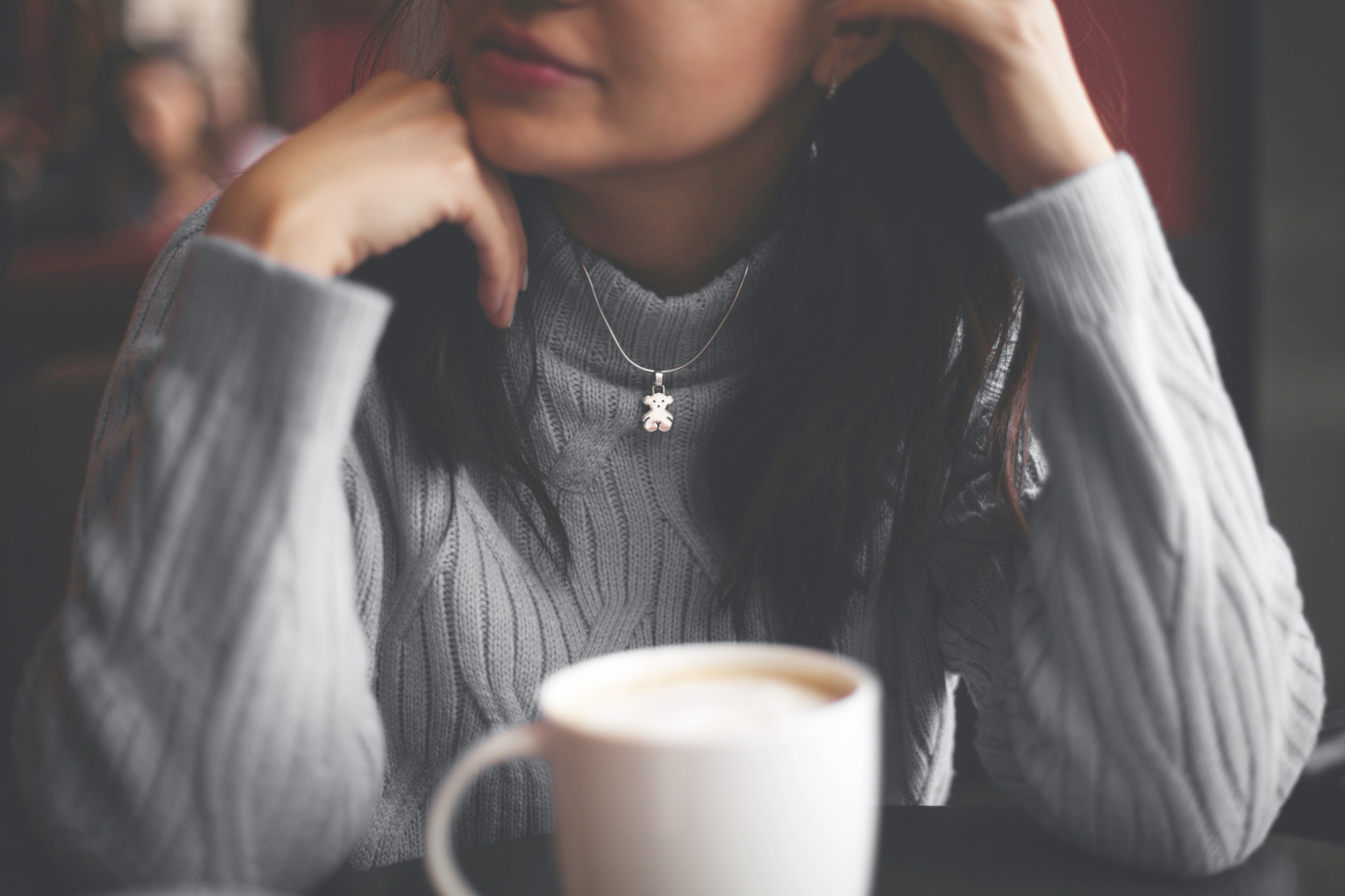 Close up of a girl in a grey sweater, wearing a silver bear necklaces, mug of coffee in the foreground. How to have an awkward first date. Brooklyn Jolley guest posts on This Splendid Shambles.