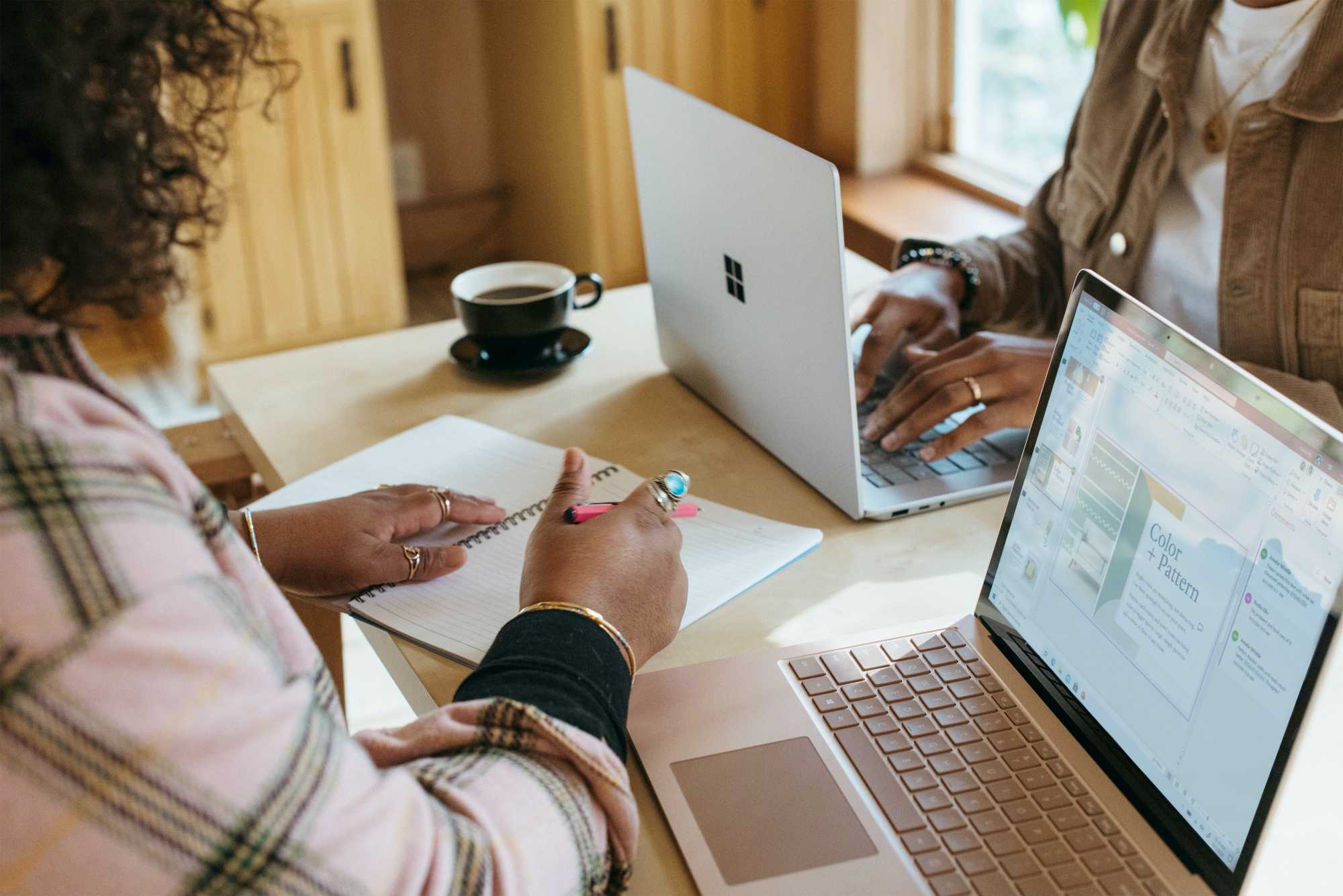 Two people at computers, one with a notebook and pen. How to stay consistent in blogging.