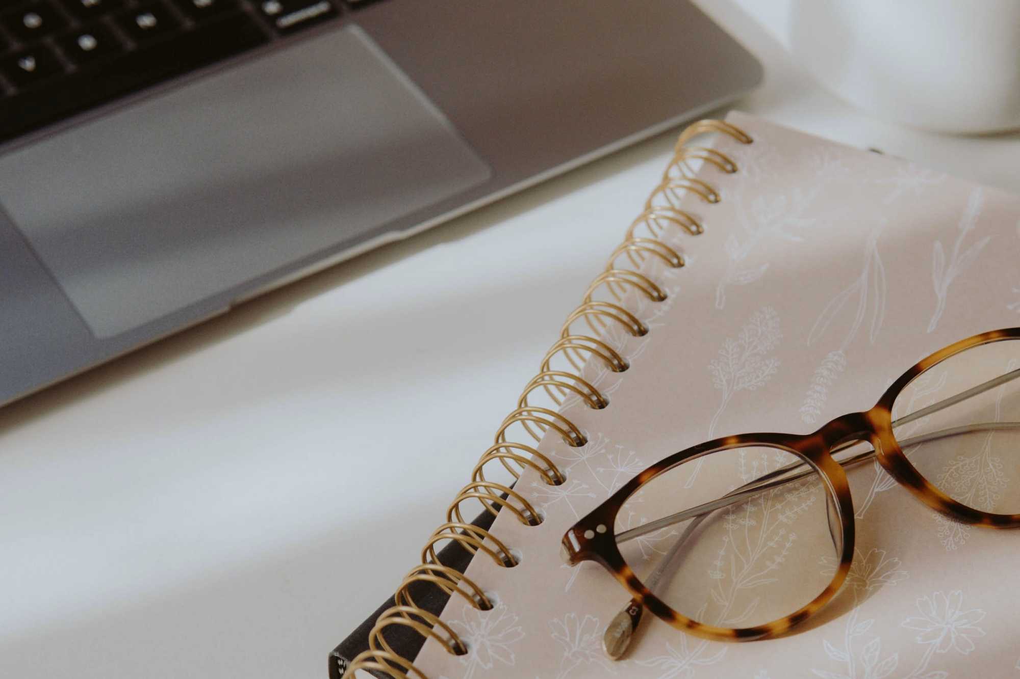 Laptop, notebook and glasses on a desk - how to write productivity at home and avoid burnout