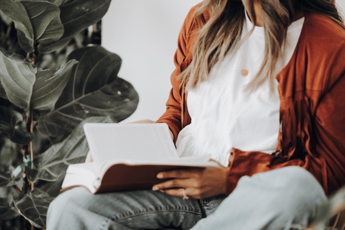 Side view of a woman wearing red and reading a book.