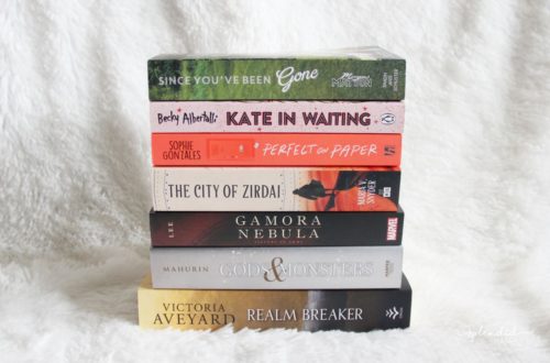 Stack of 7 books on a white blanket. Book haul on This Splendid Shambles.