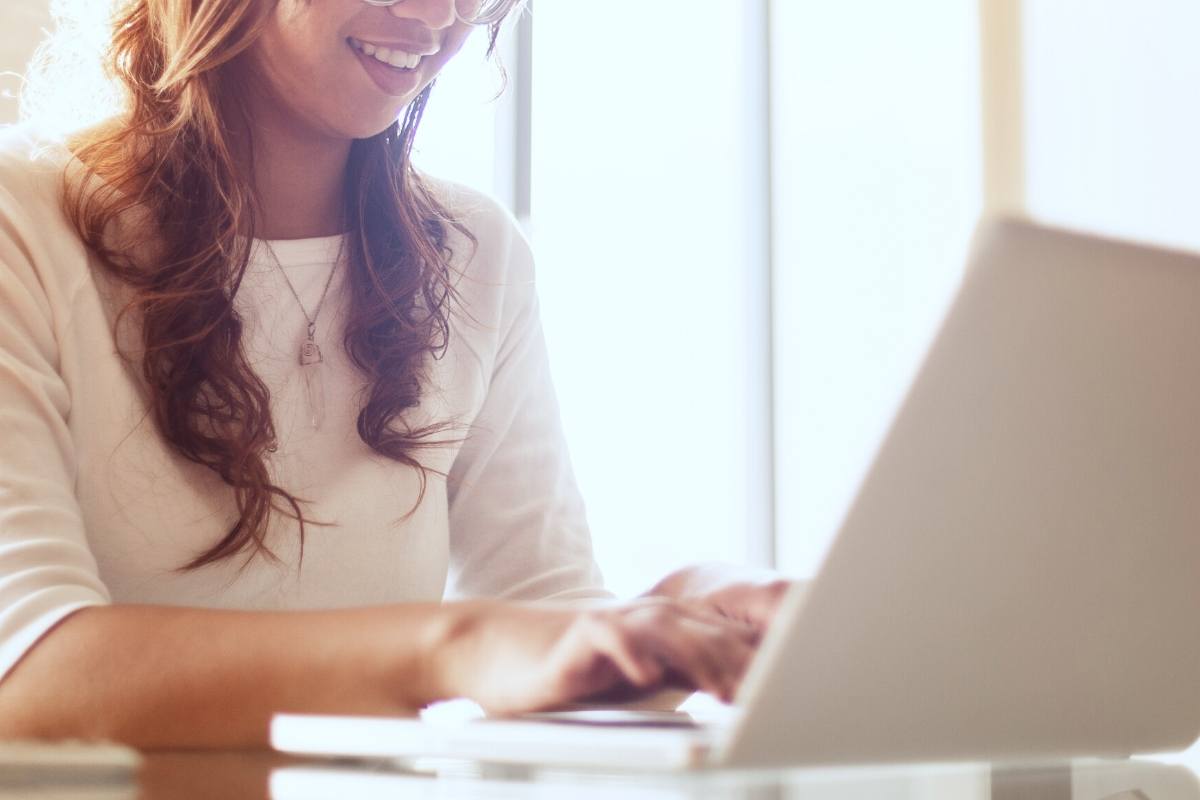 Woman sitting at a table with her fingers on a laptop keyboard. The best hosting platform for new bloggers - Lyrical Host - This Splendid Shambles