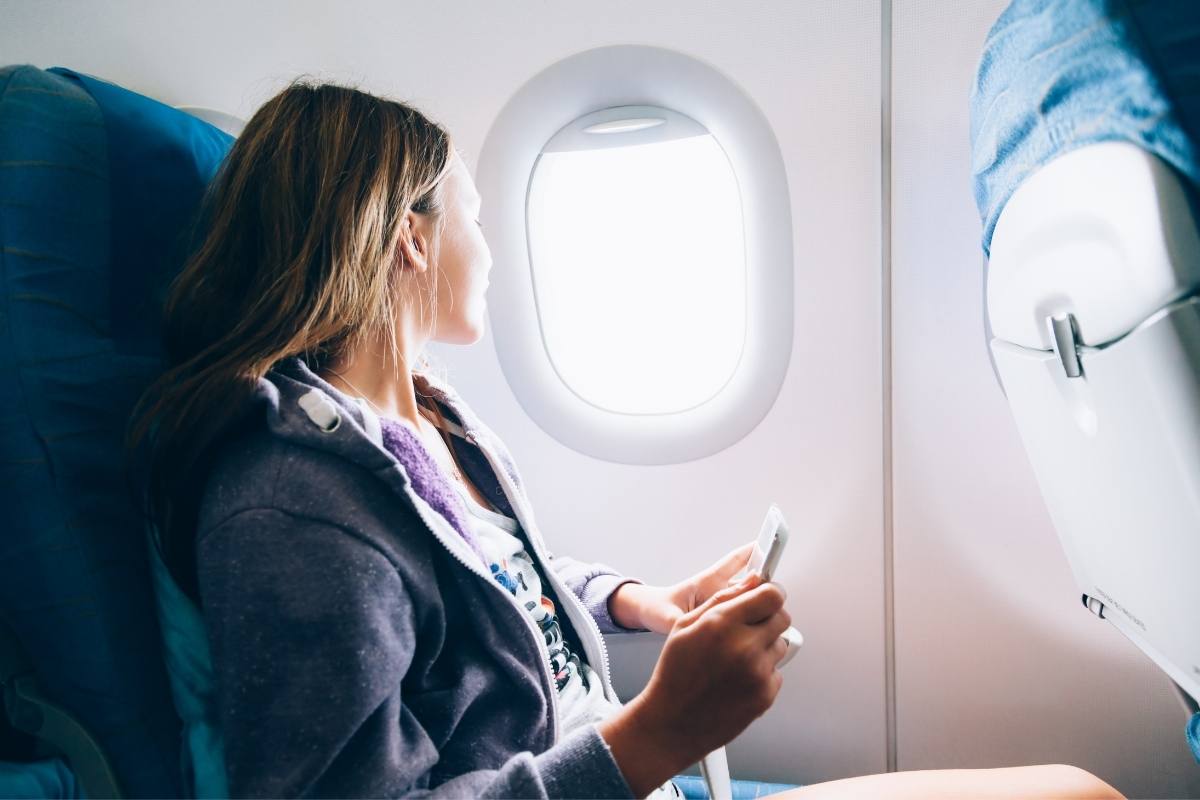 A woman looking out the window of a plane. How to travel well - top tips for travelling with ease on This Splendid Shambles. 