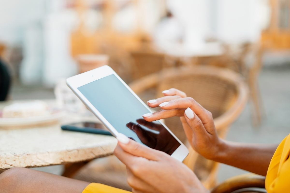 A woman's hands holding a kindle, with her other hand posed over the screen.