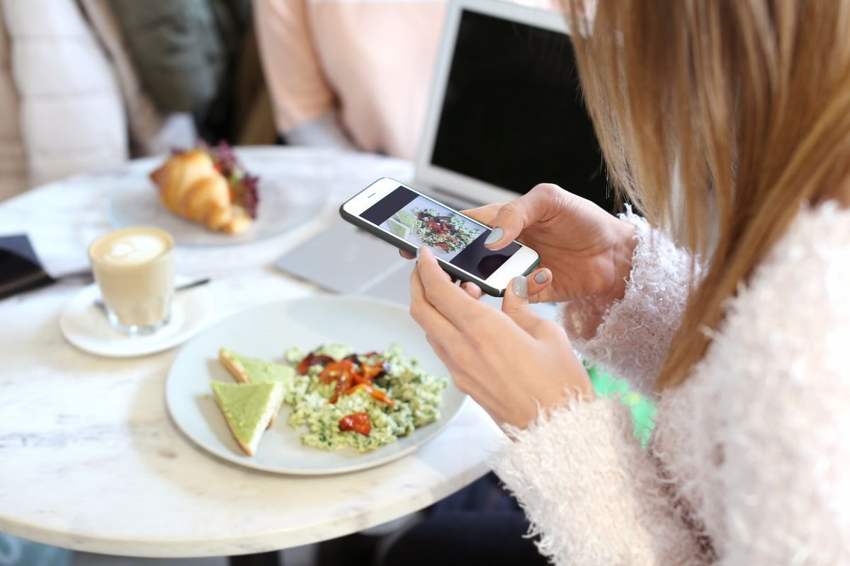 Woman at a restaurant using her phone to take a photo of her meal. 