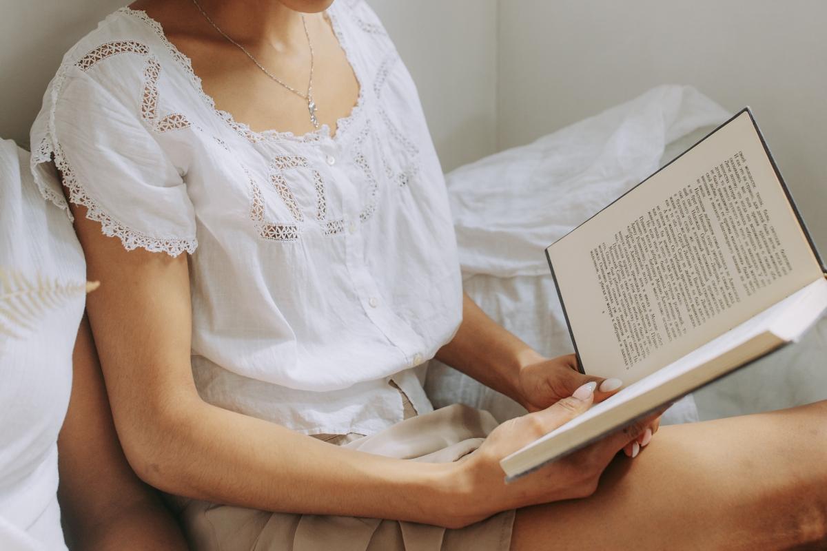 A woman in a white shirt holding an open book. 