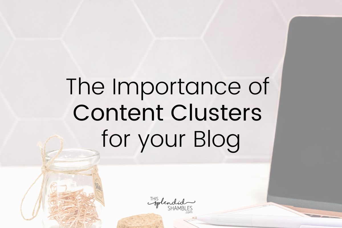 Laptop on the right of the image, sitting on a white table, various stationery items to the left. 'The Importance of Content Clusters for your blog' written on top.